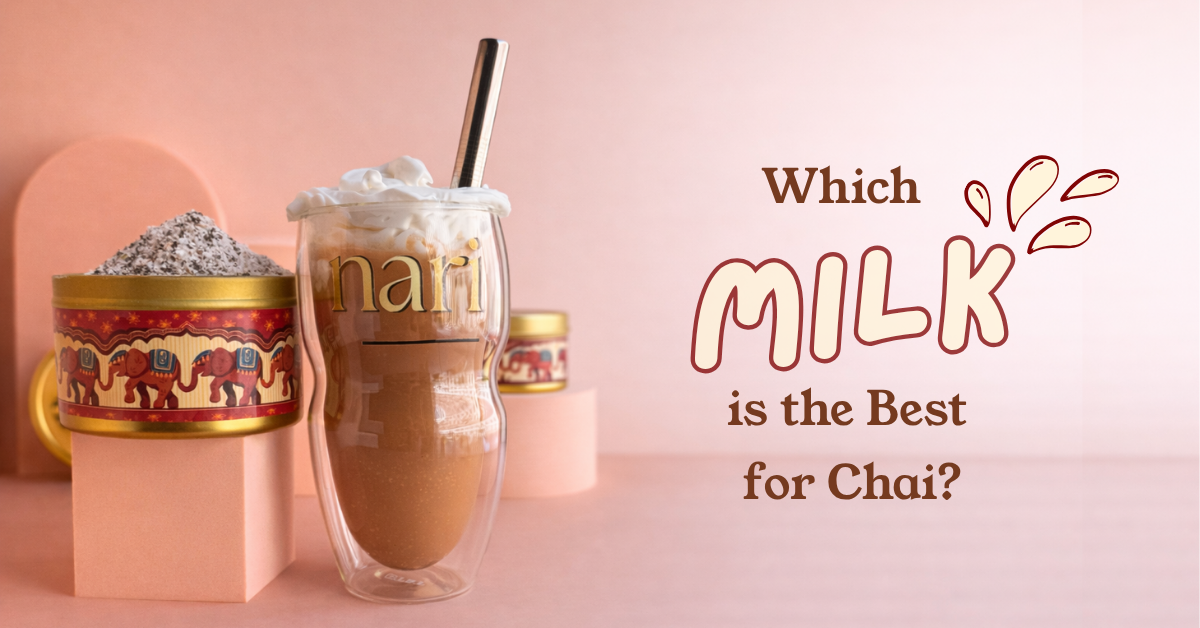 A double-walled clear glass cup filled with Nari masala quick brew chai drink and topped with whipped cream, with a metal straw. The cup has the word 'nari' printed on it.